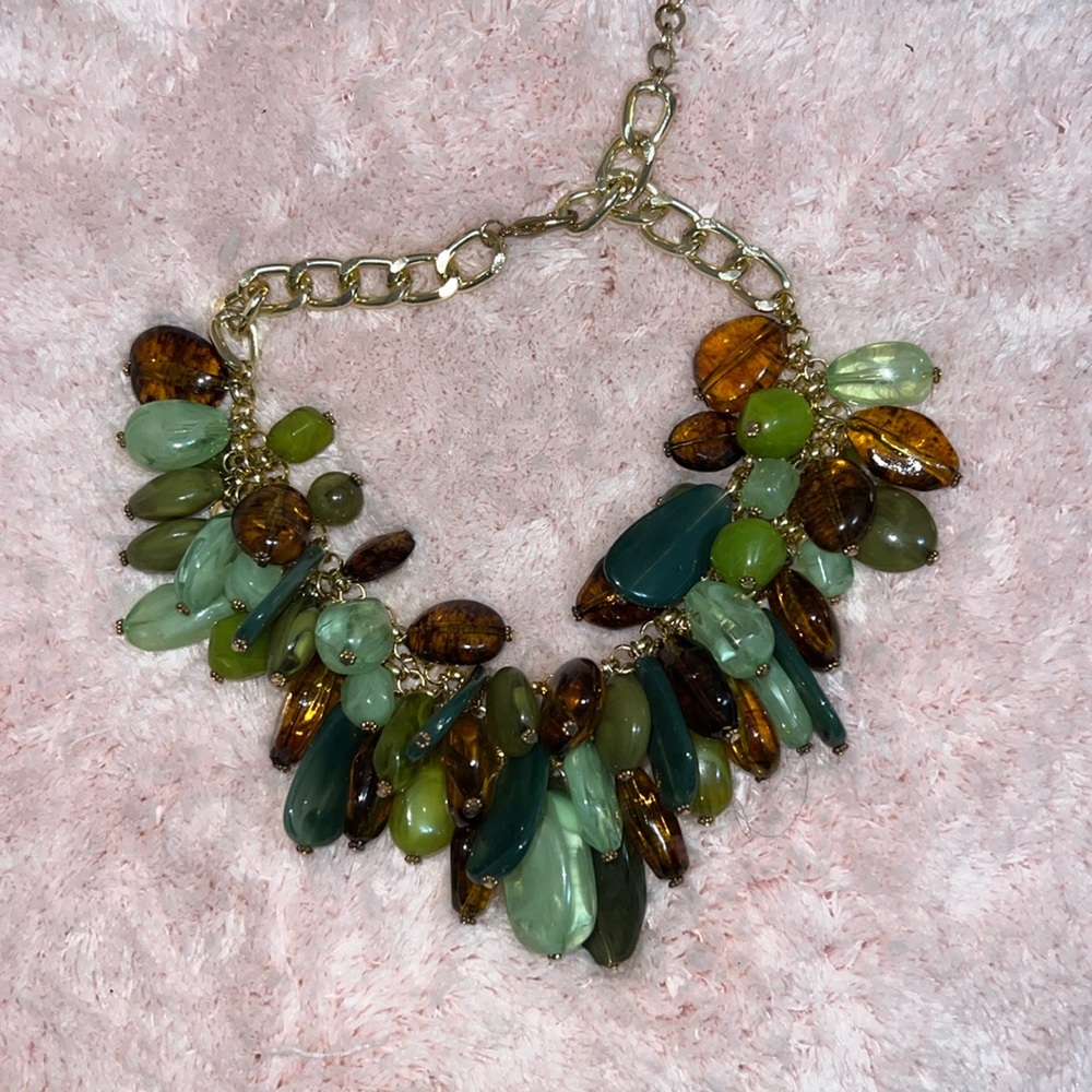 Gold chained necklace with green and brown emeralds